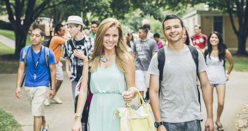 Students walking towards camera on campus, smiling